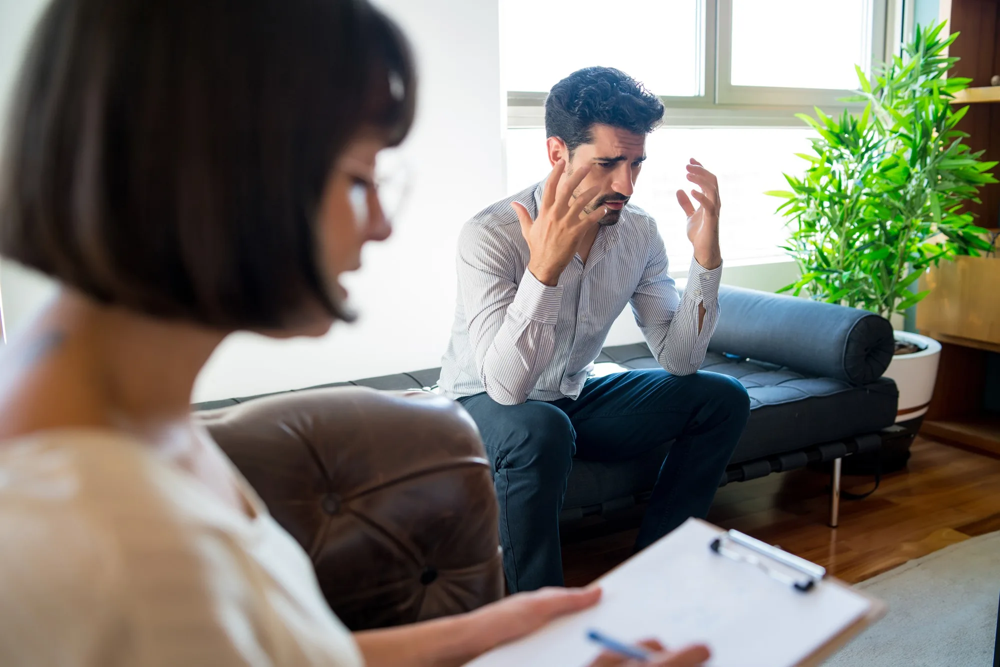 Man sharing his feelings with a therapist holding a clipboard