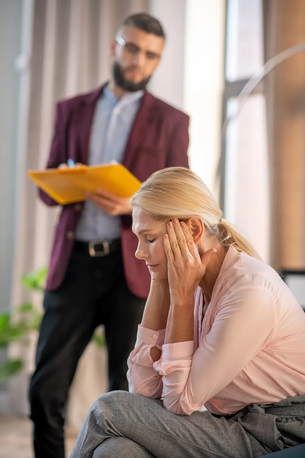 Woman sitting with her head in her hands as a man comforts her