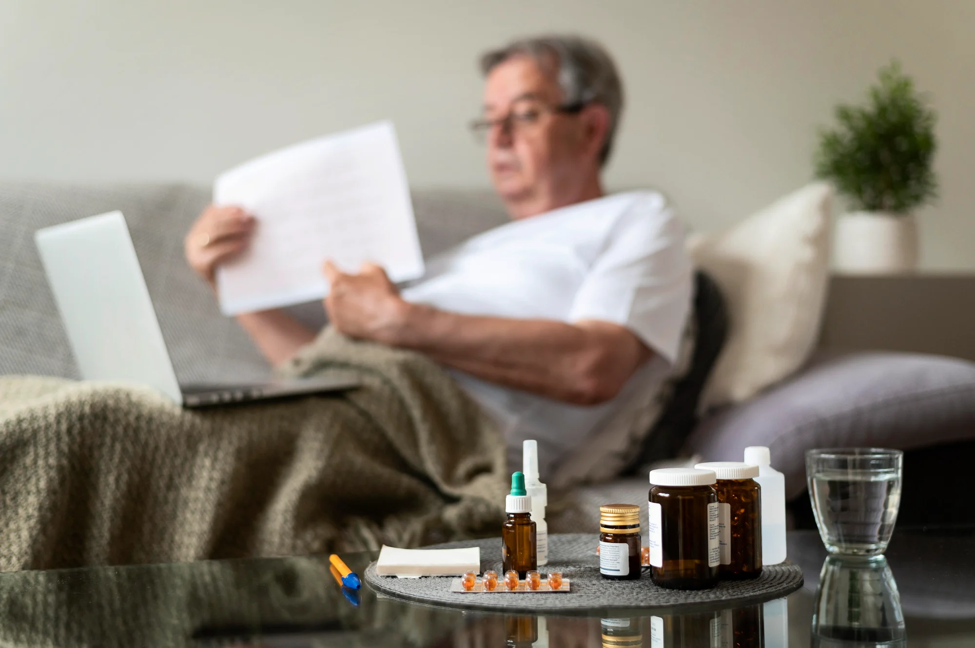 Man resting on a couch at home with medications on a side table